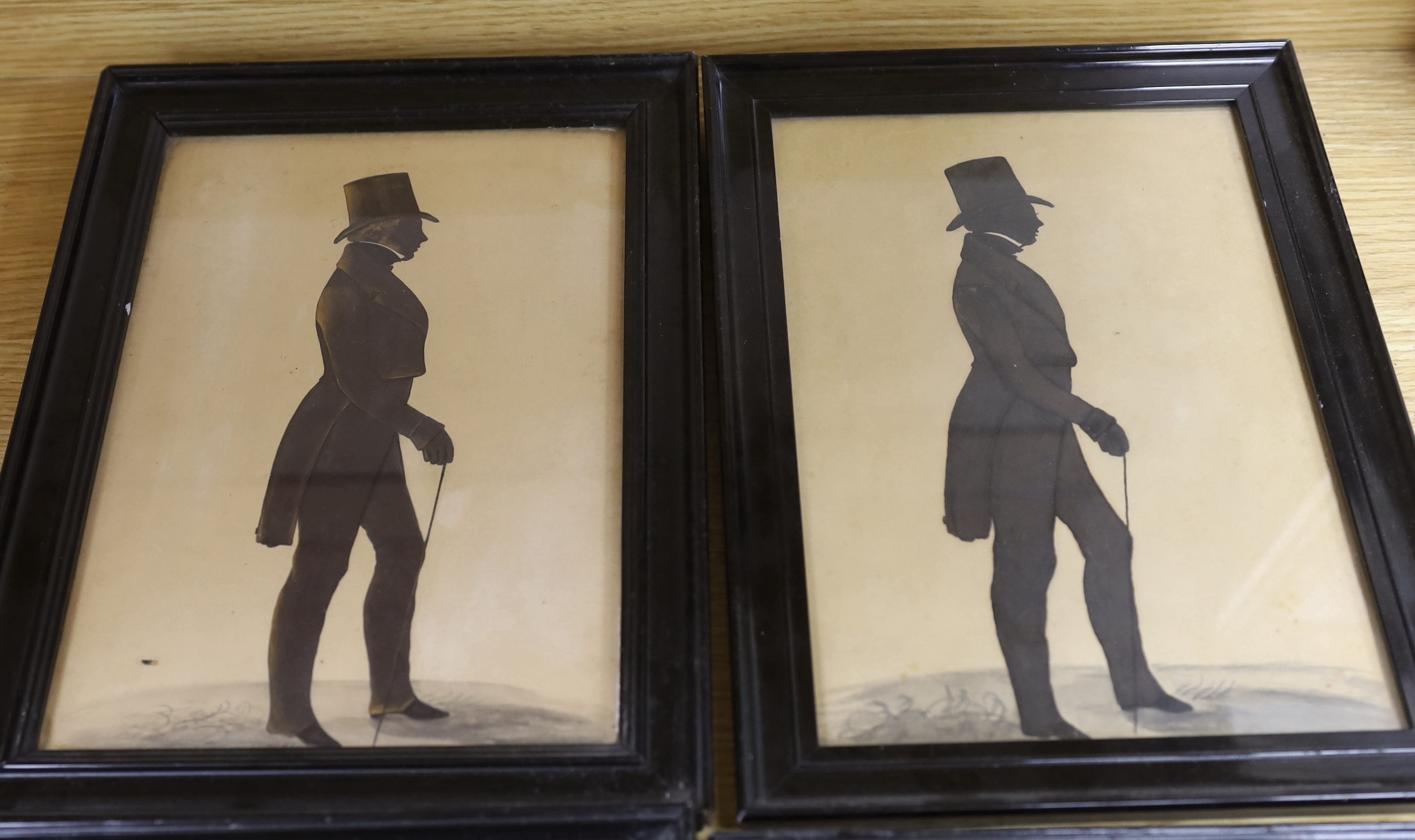 Victorian School, four cut and bronzed paper silhouettes, Full length profiles of gentlemen wearing frock coats and top hats, largest 28 x 18cm